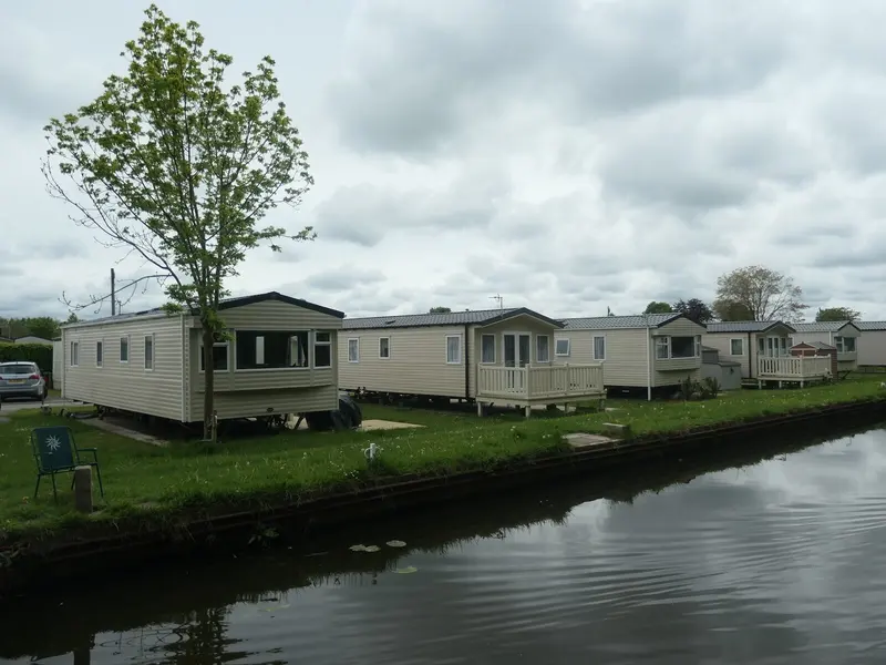 Static caravans with decking beside a canal on a holiday park